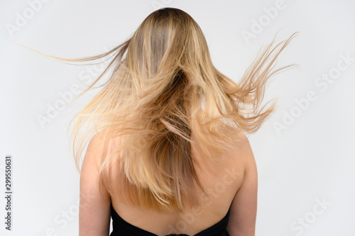 Studio large photo portrait of a beautiful girl with long beautiful fluttering hair on a white background. Back view.