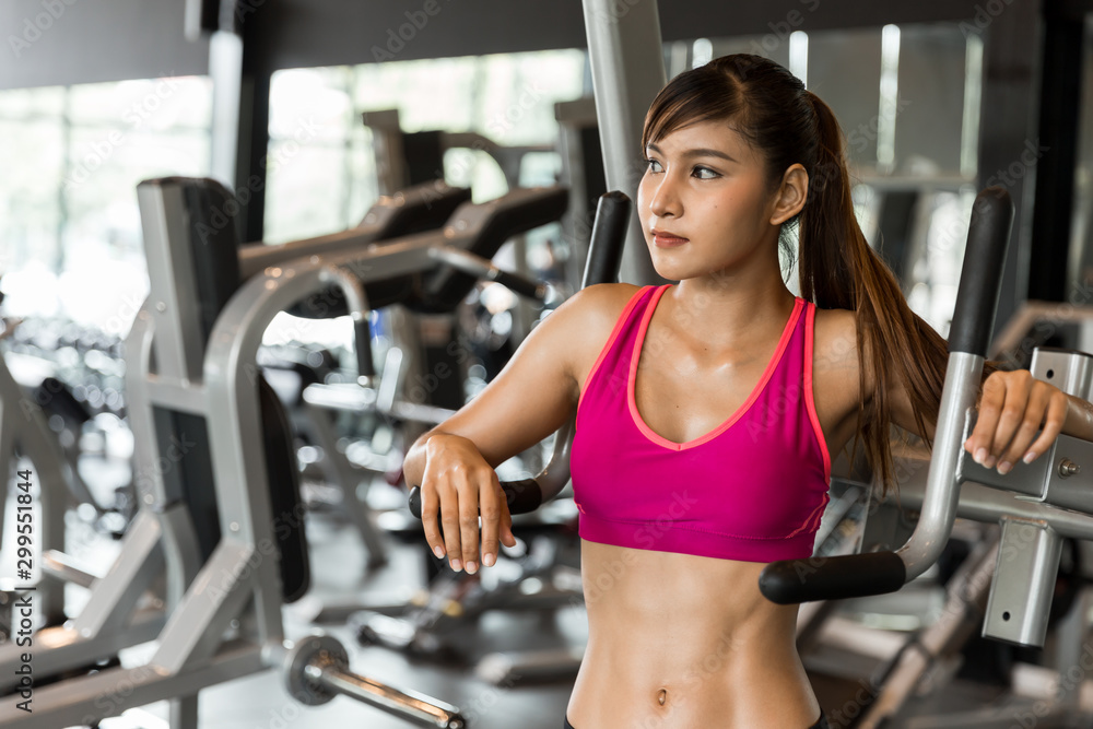 Young happy healthy attractive muscular Asian woman showing six pack abs standing in the gym, sport and fitness concept. Young happy healthy attractive muscular Asian woman showing six pack abs standing in the gym, sport and fitness concept.