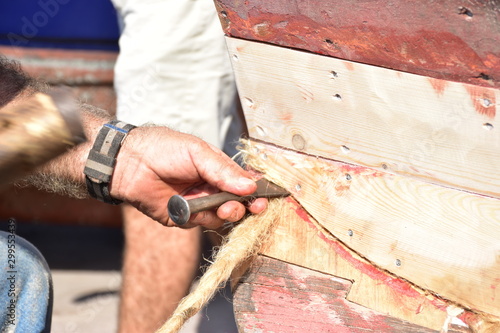  Calafataggio,  tecnica di impermeabilizzazione dello scafo in legno, eseguita dal mastro calafato. Lavoro eseguito su una barca tradizionale in legno. Sicilia, Palermo- località Sferracavallo photo