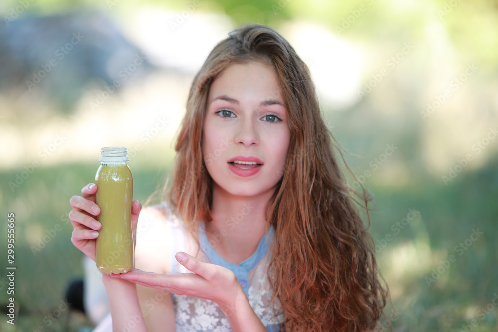 Jeune fille dégustant un smoothie allongée dans l'herbe en été Jeune fille dégustant un smoothie allongée dans l'herbe en été