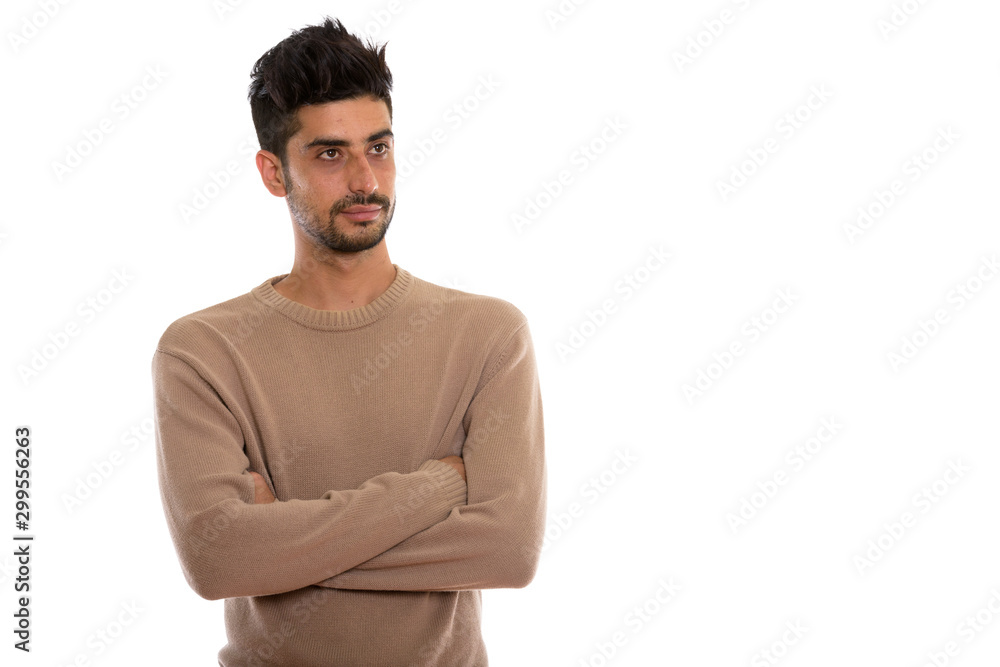 Studio shot of young Persian man thinking with arms crossed Studio shot of young Persian man thinking with arms crossed