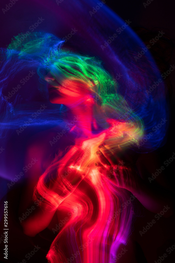 Conceptual avant-garde portrait of a beautiful young girl covered with multicolored lines applied by a light brush. Art style creative photo. Advertising, fashion and commercial design. Conceptual avant-garde portrait of a beautiful young girl covered with multicolored lines applied by a light brush. Art style creative photo. Advertising, fashion and commercial design.
