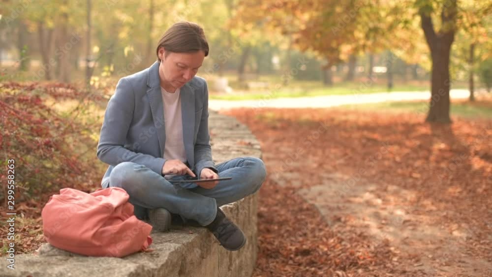 Businesswoman reading e-book on digital tablet in autumnal park Businesswoman reading e-book on digital tablet in autumnal park
