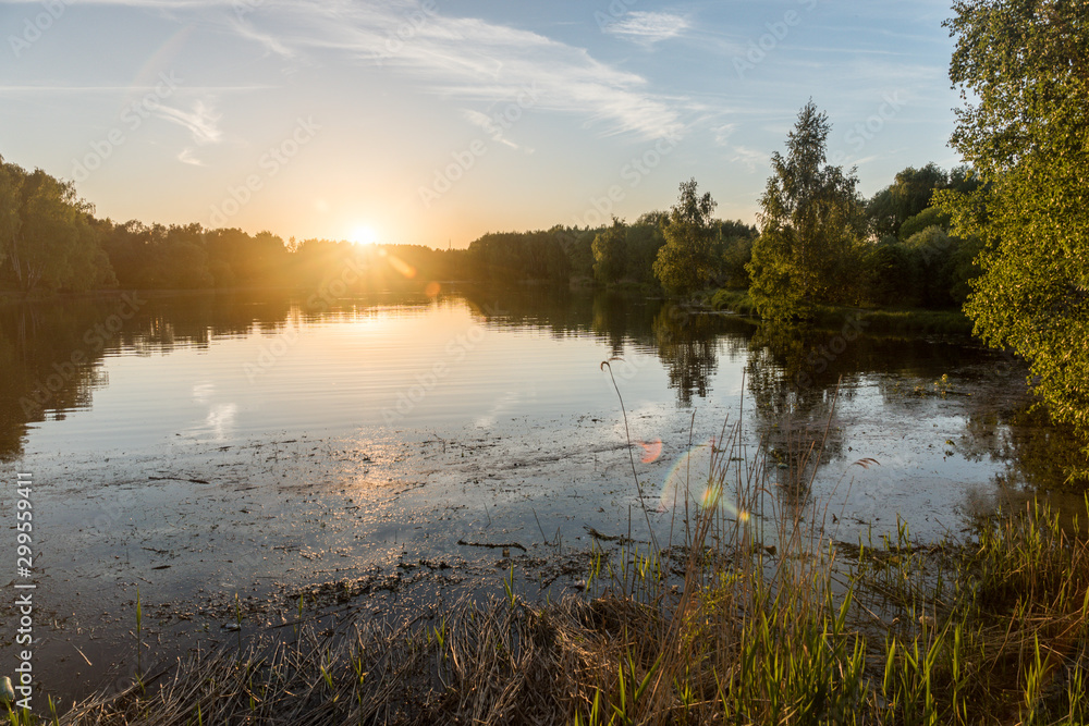 Fototapeta premium summer riverscape with blue sky, clouds, sunset and water reflections