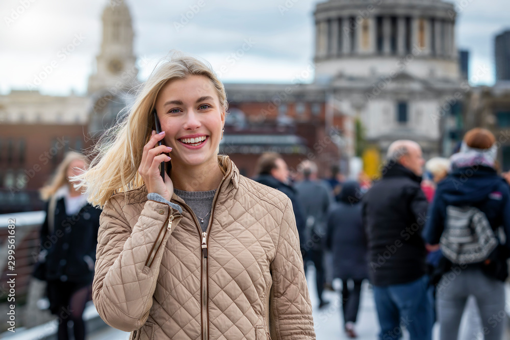 Eine attraktive, blonde Frau in der Stadt telefoniert mit ihrem Mobiltelefon Eine attraktive, blonde Frau in der Stadt telefoniert mit ihrem Mobiltelefon