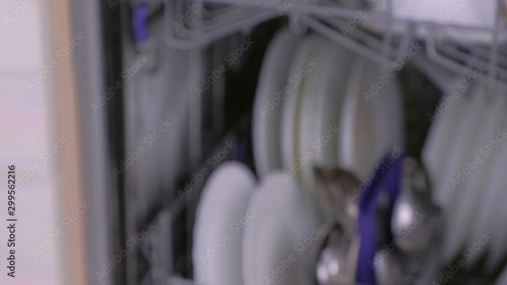 Man's hand is closing dishwasher with dirty white dishes. Hand close-up, side view. Man's hand is closing dishwasher with dirty white dishes. Hand close-up, side view.