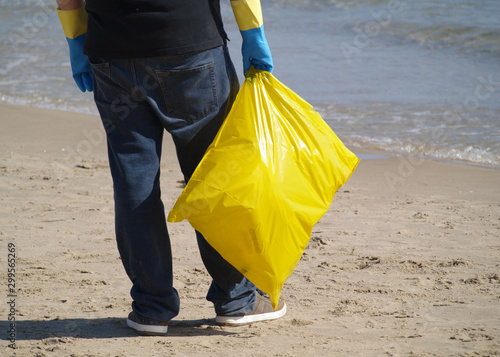 Man looking at the ocean with a bag of recycled plastic