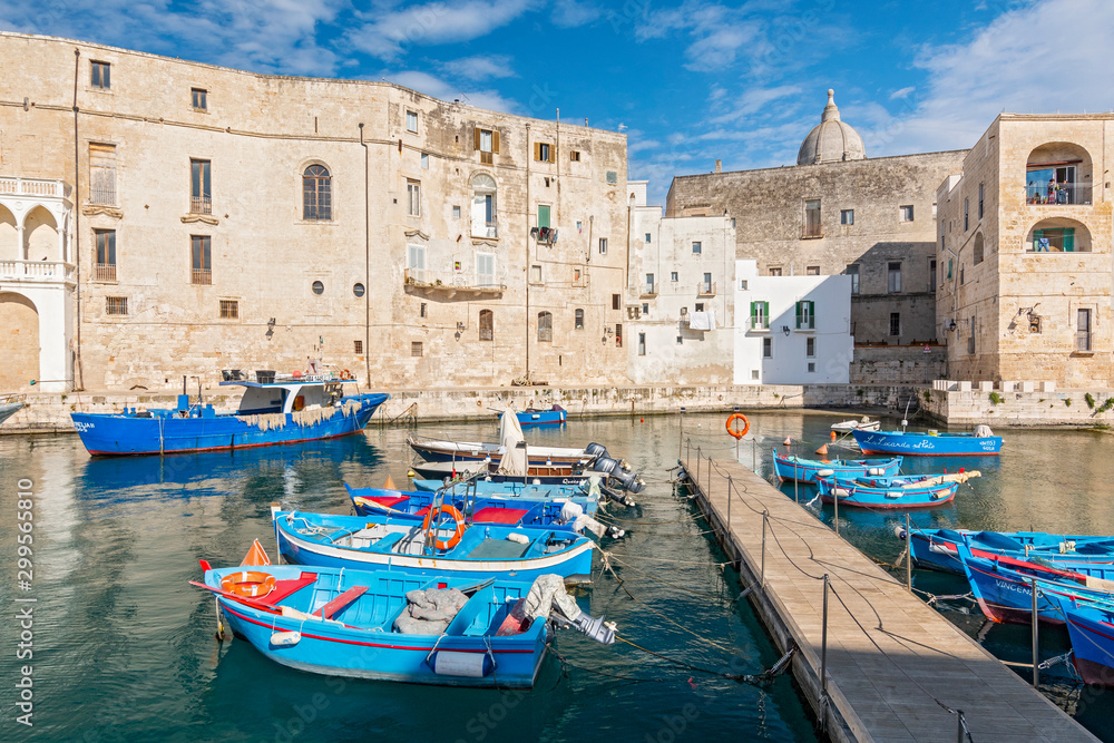 View of Monopoli harbor with colorful azure fishing boats, Apulia, Italy.