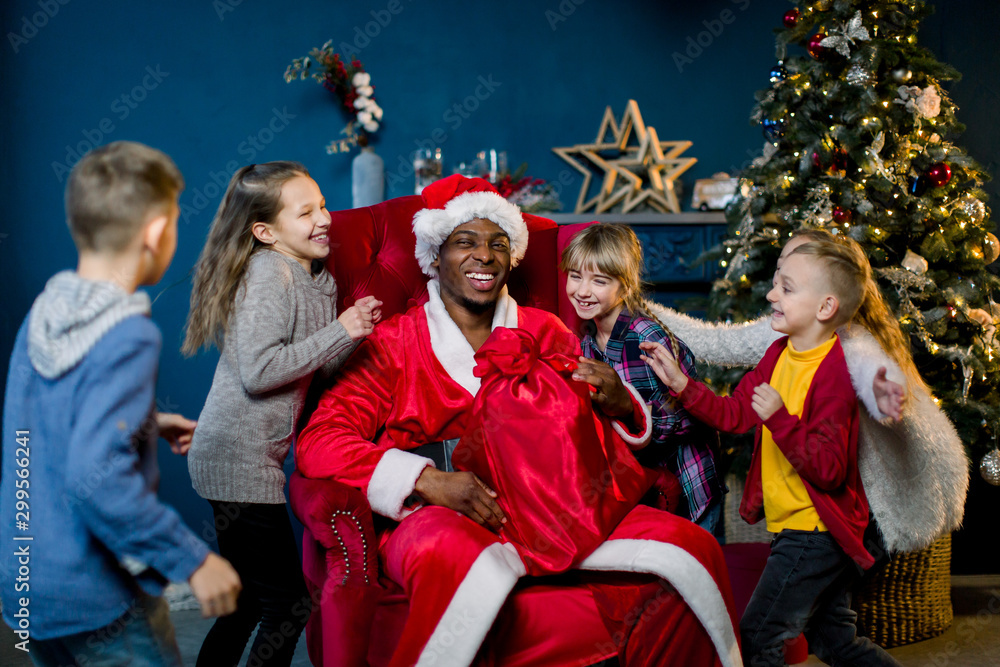 African Santa Claus and happy little children on the background of the Christmas tree