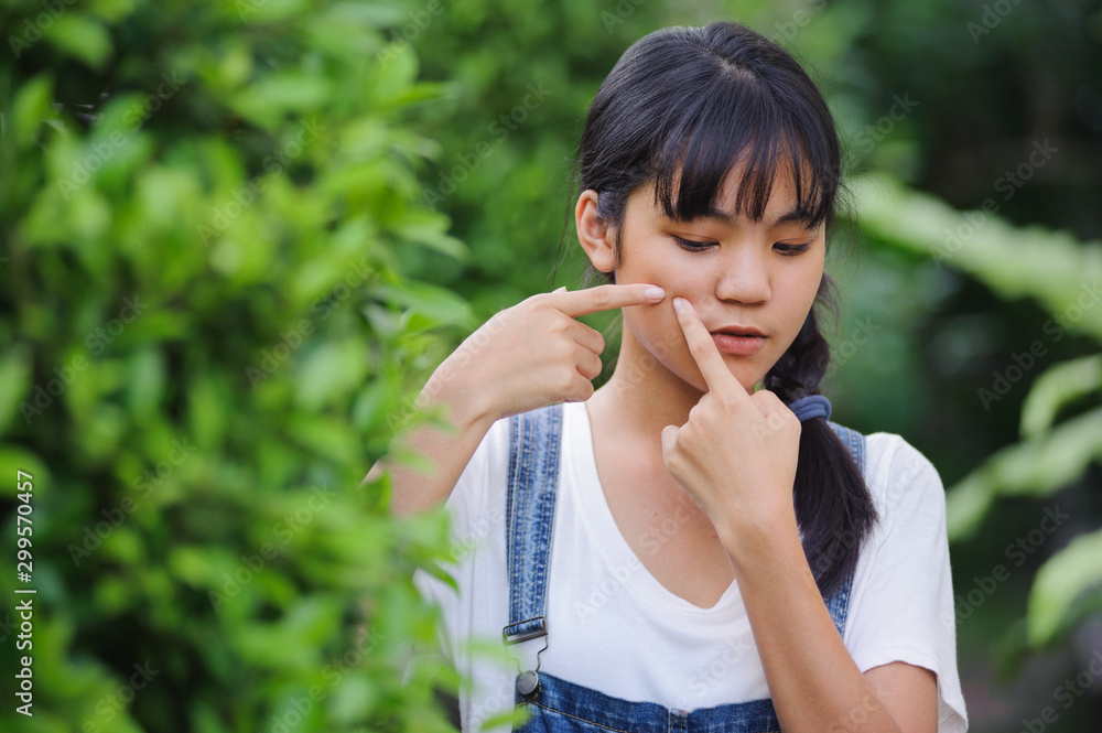 asian girl pigtail hair wearing white shirt and jean overall squeezing pimple in the garden asian girl pigtail hair wearing white shirt and jean overall squeezing pimple in the garden