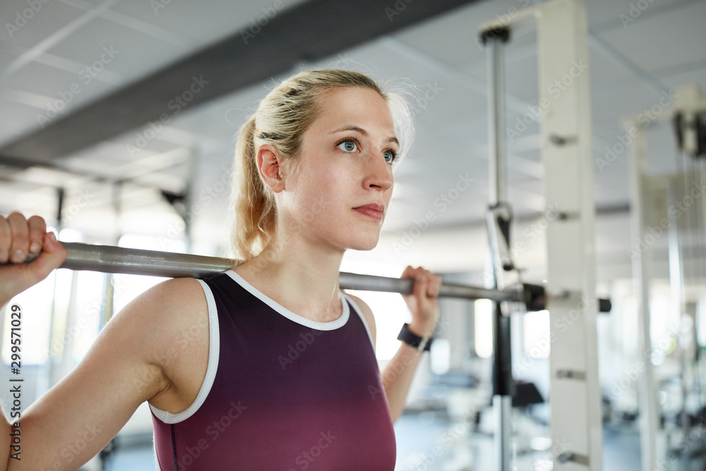 Obraz premium Junge Frau trainiert in der Langhantelstation