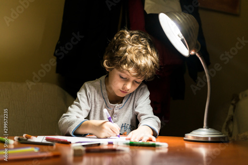 Child drawing illuminated by the light of a lamp.