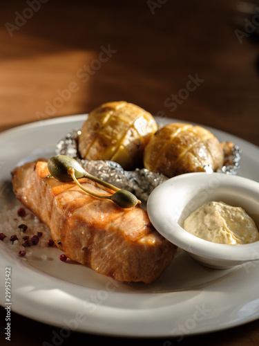 grilled salmon steak and baked potatoes with sauce