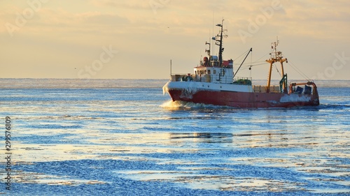 Frozen fishing vessel in coming back to the port at the sunset