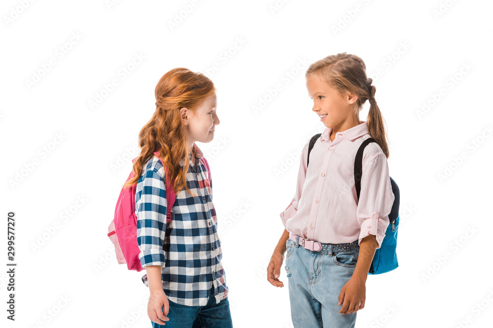 happy schoolkids with backpacks looking at each other isolated on white happy schoolkids with backpacks looking at each other isolated on white
