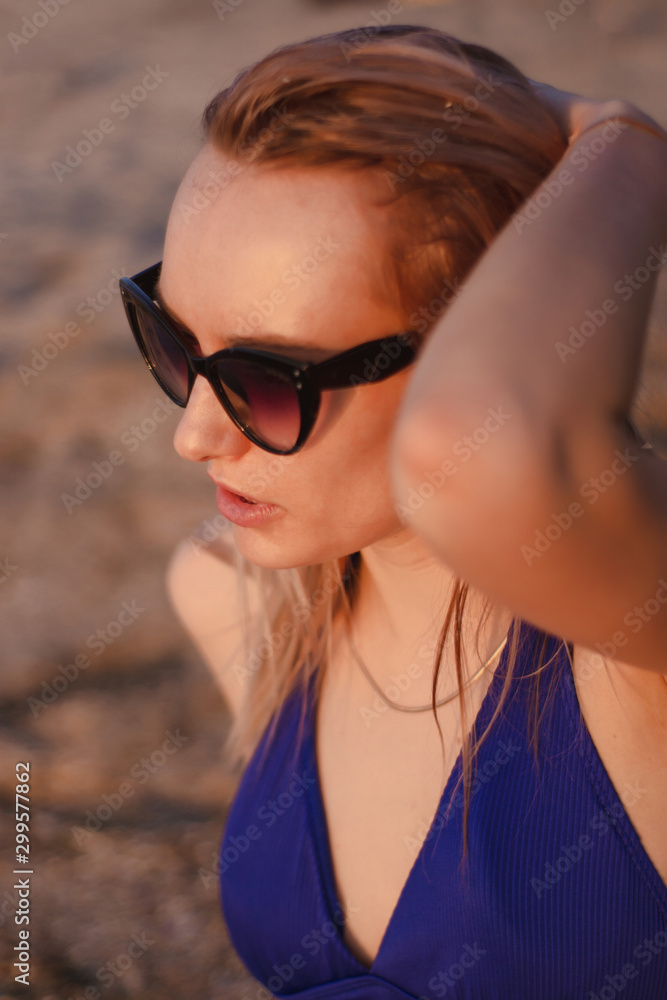 happy young woman in a swimsuit and suglasses walking on the beach, model posing happy young woman in a swimsuit and suglasses walking on the beach, model posing