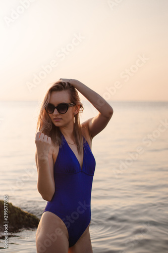 happy young woman in a swimsuit and suglasses walking on the beach,  model posing