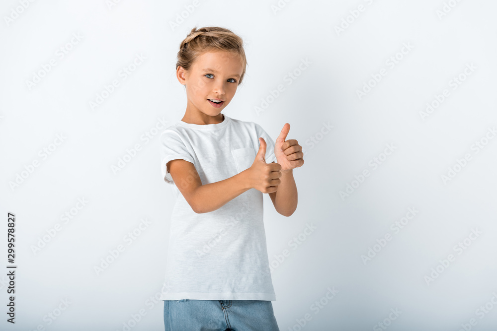 cheerful kid looking at camera and showing thumb up on white cheerful kid looking at camera and showing thumb up on white