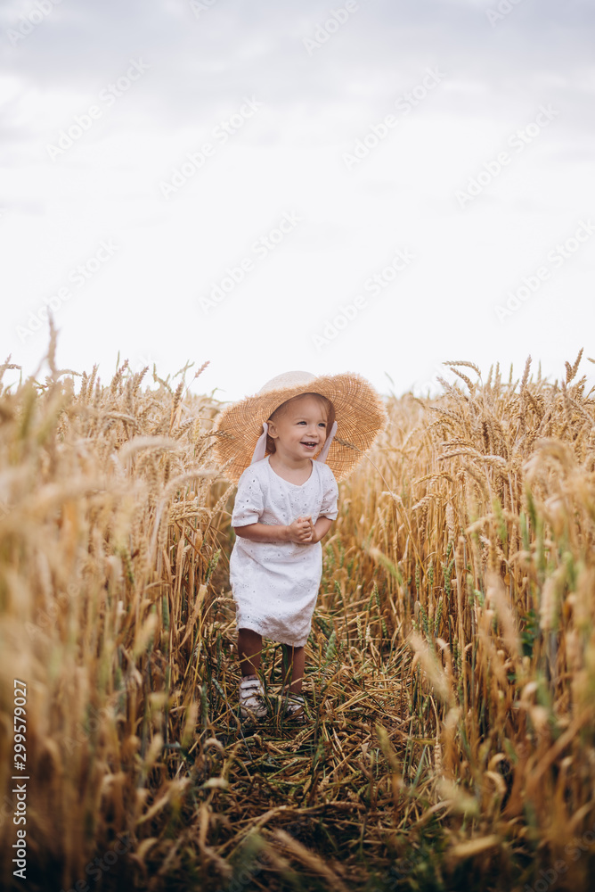 Cute smiling baby girl 1-2 year old wearing straw hat and short cut hair posing outdoors over nature background. Looking at camera. autumn season. Childhood. Cute smiling baby girl 1-2 year old wearing straw hat and short cut hair posing outdoors over nature background. Looking at camera. autumn season. Childhood.