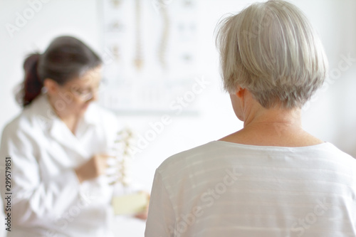 Aging and back pain concept: senior patient consulting her physician because of herniated disk.