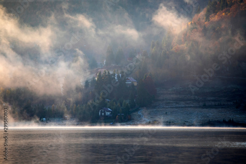 Lovely autumnal landscape with fog over the lake.