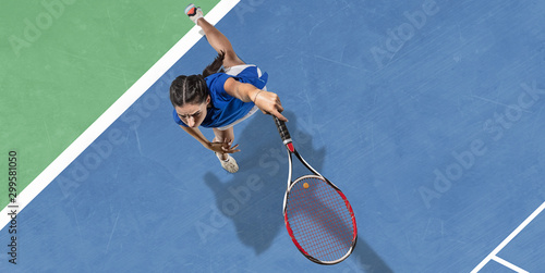 Young caucasian brunette woman in blue shirt playing tennis at the court. Hits ball with racket, outdoors. Youth, flexibility, power, energy. Copyspace. Top view. Motion, action, healthy lifestyle. © master1305