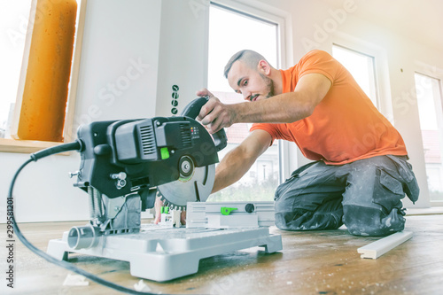 craftsman cuts wood plank with the chop saw on the construction