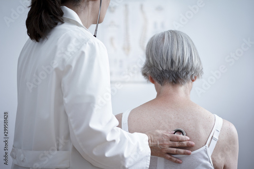 Health care concept: female doctor auscultating the lungs of a senior patient with a stethoscope. photo
