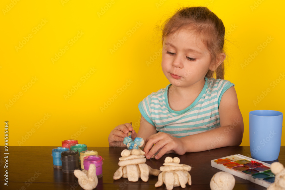 Little girl paints toy animals paints on a yellow background Little girl paints toy animals paints on a yellow background