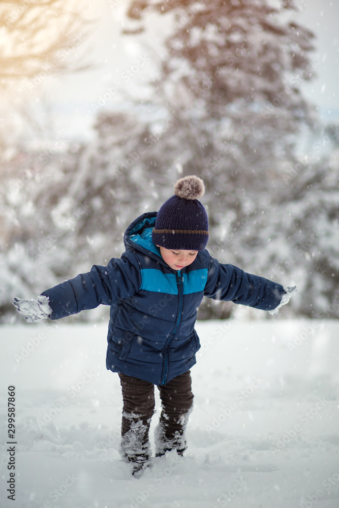 Adorable, cute boy playing with snow cheerfully