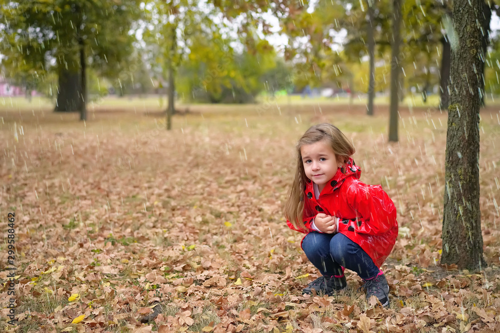 Little girl in raincoat playing on the rainy day in park Little girl in raincoat playing on the rainy day in park