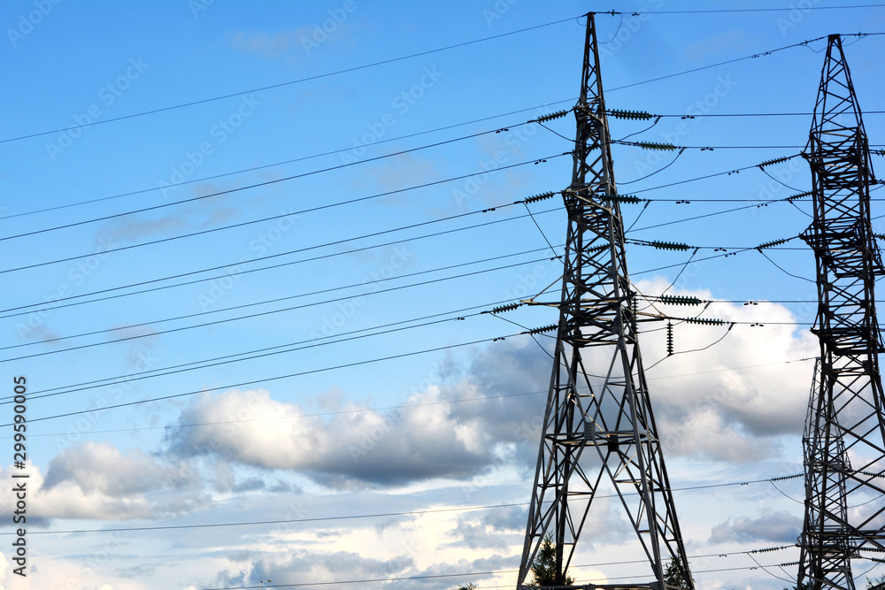 Towers of electric main with the wires against the blue sky with clouds ...