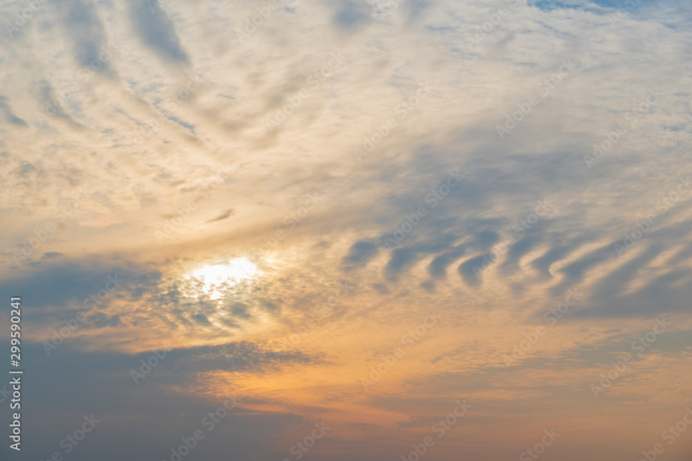 Cloudscape. The clouds in the sky form patterns, ripples, bizarre stripes and bends that are illuminated by the glow of the setting sun. Natural background.