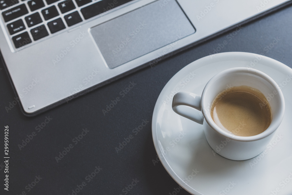 escritorio oscuro con taza de café caliente y ordenador portátil escritorio oscuro con taza de café caliente y ordenador portátil
