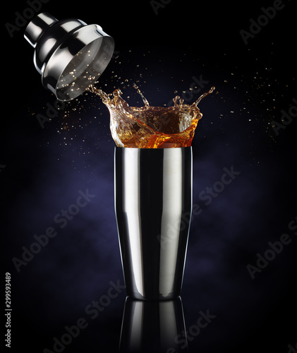 Foto amber liquor spilling out of a shaker isolated on dark blue background