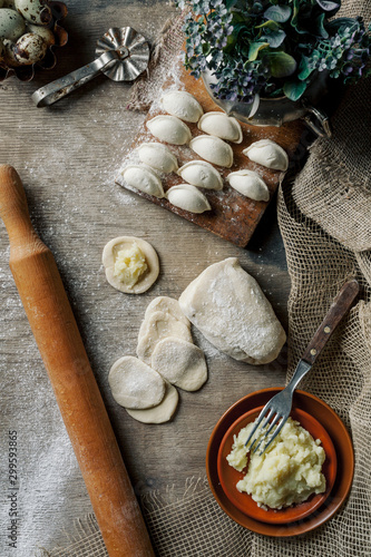 Raw dumplings on a wooden board. Traditional homemade food. The process of making dumplings. Slavic traditional dish. Dough for dumplings. Potato dumplings. Flour. View from above.