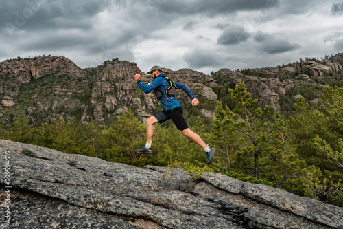 Athlete runner runs on a rock in the mountains. Trail running