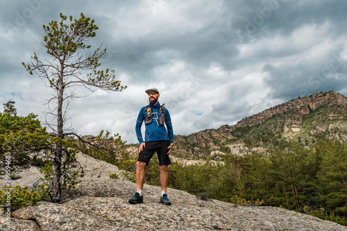 male runner standing on a rock in the mountains
