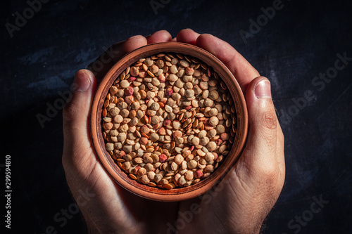 Hands holding a clay bowl with lentil grains