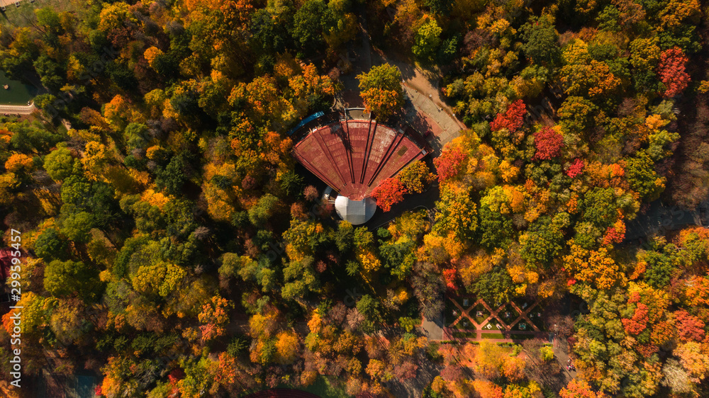 Old abandoned building in the autumn park among bright colored trees, aerial view