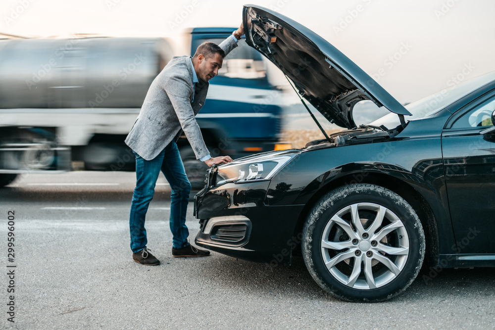 Elegant middle age business man trying to fix car breakdown or engine failure and waiting for towing service for help car accident on the road. Roadside assistance concept. Elegant middle age business man trying to fix car breakdown or engine failure and waiting for towing service for help car accident on the road. Roadside assistance concept.