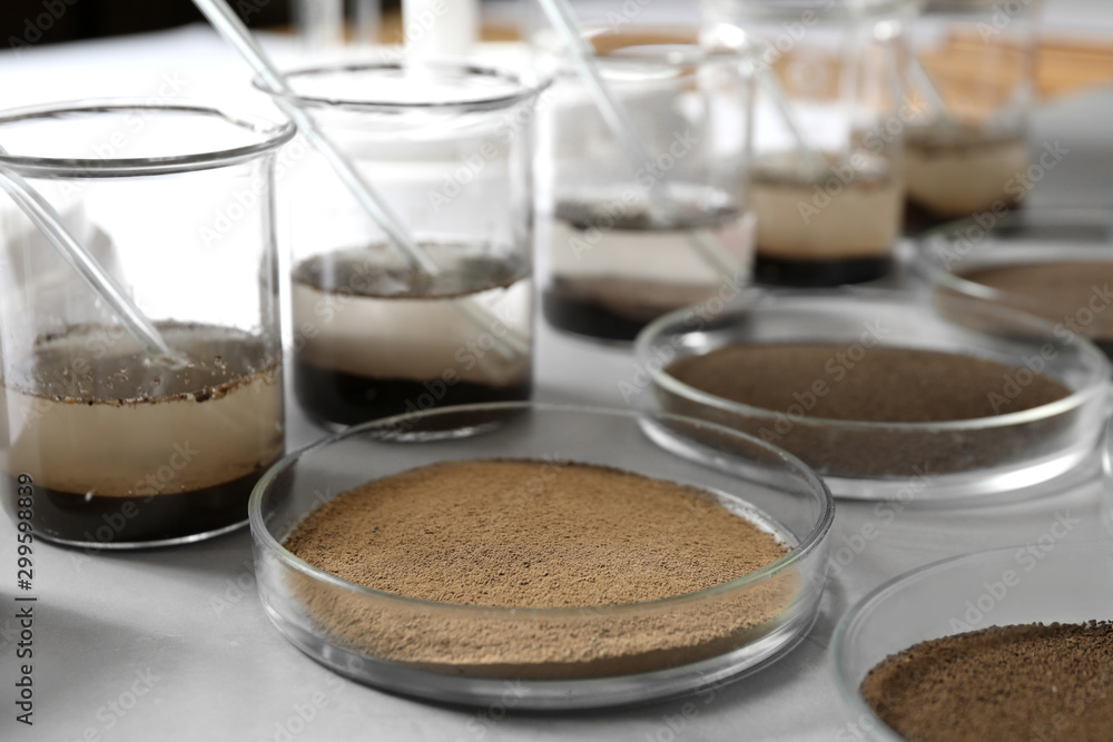 Glassware with soil samples and extracts on light table. Laboratory research Glassware with soil samples and extracts on light table. Laboratory research