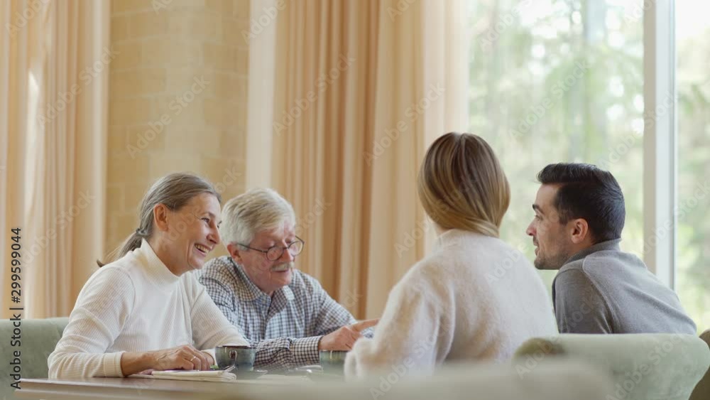 Side view shot of elderly parents having dinner in restaurant with adult son and his girlfriend. Two couples, young and senior ones, talking joyfully over tea Side view shot of elderly parents having dinner in restaurant with adult son and his girlfriend. Two couples, young and senior ones, talking joyfully over tea