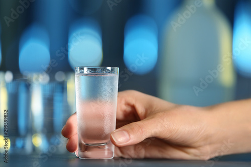 Woman with shot of vodka at table in bar, closeup
