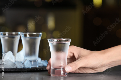 Woman with shot of vodka at table in bar, closeup