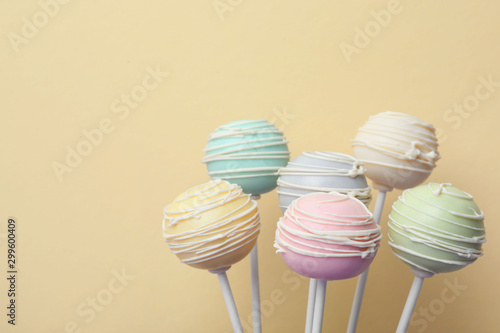 Sweet colorful cake pops on yellow background