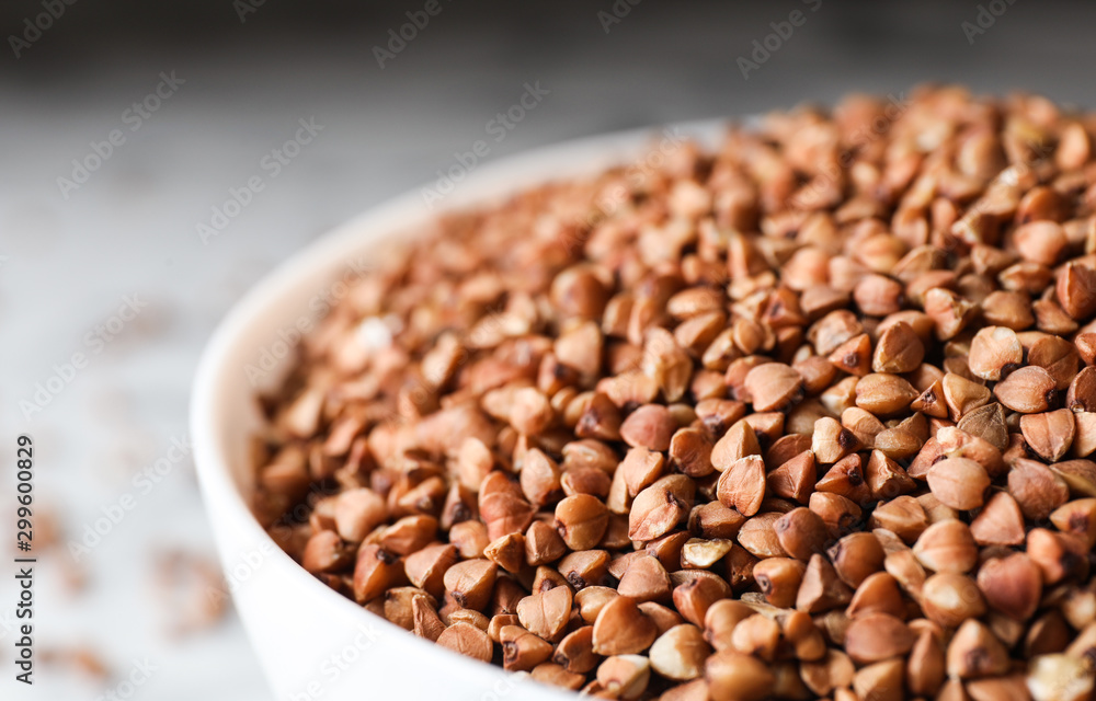 Uncooked organic buckwheat grains in bowl, closeup Uncooked organic buckwheat grains in bowl, closeup