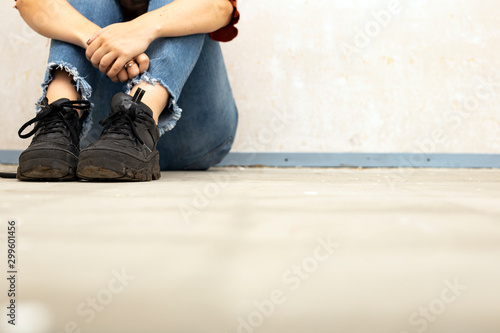 Young woman sitting on the floor in a new home, needs renovation, space for text