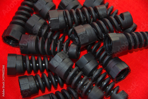 Black plastic and rubber parts of automotive manufacturing by high precision mold injection in the industrial factory. Spare part in the form of a spiral spring on a red surface. Selective soft focus.