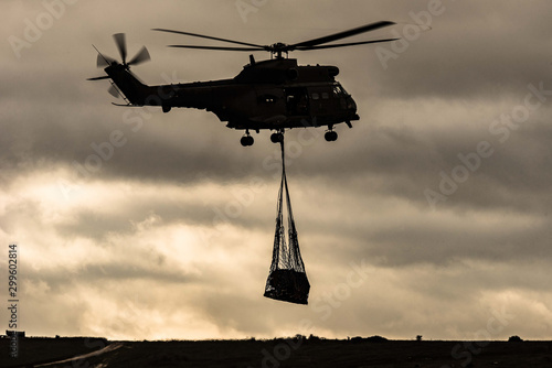 Puma military helicopter carries underslung load at dusk photo